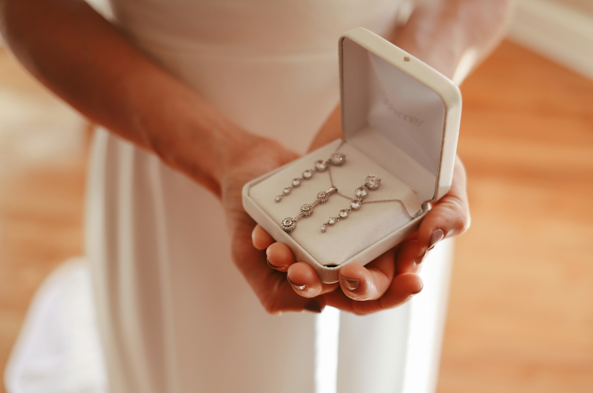 Bride holding elegant bridal jewelry set in white box