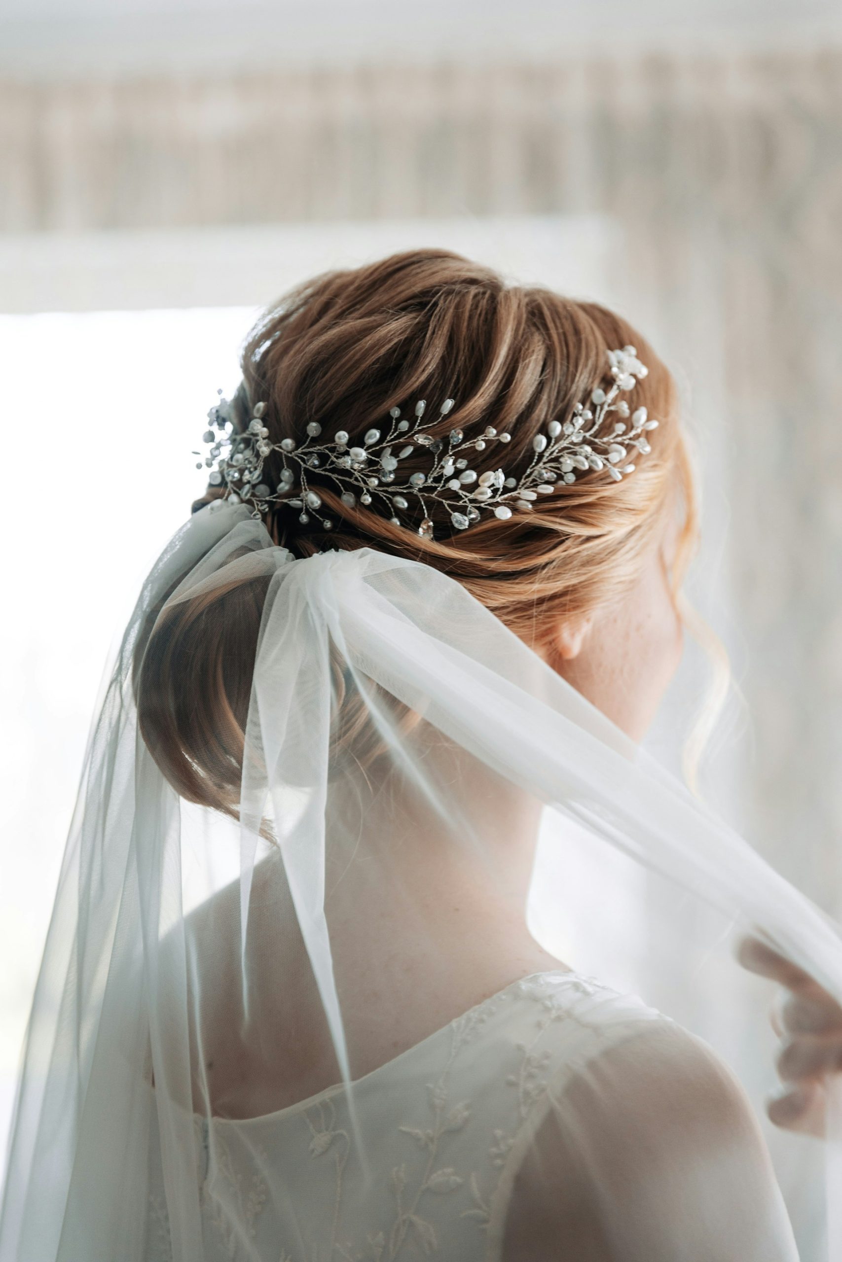 Bride with elegant updo and pearl hair accessory under sheer