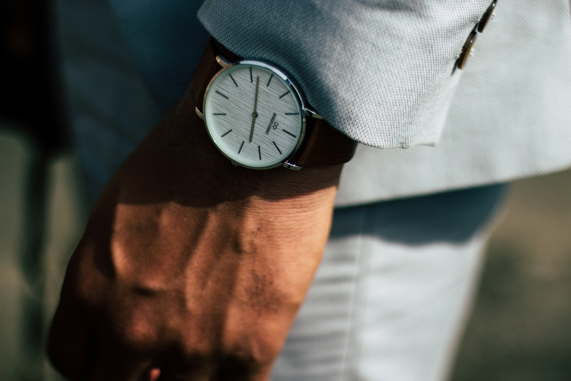 Man wearing a stylish silver wristwatch with white dial